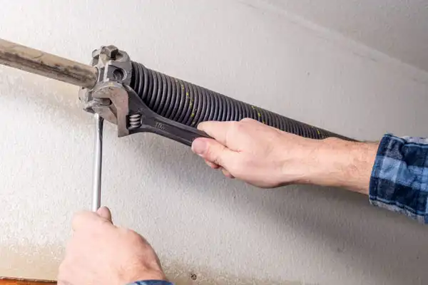 A [account_name] technician replacing a commercial garage door spring